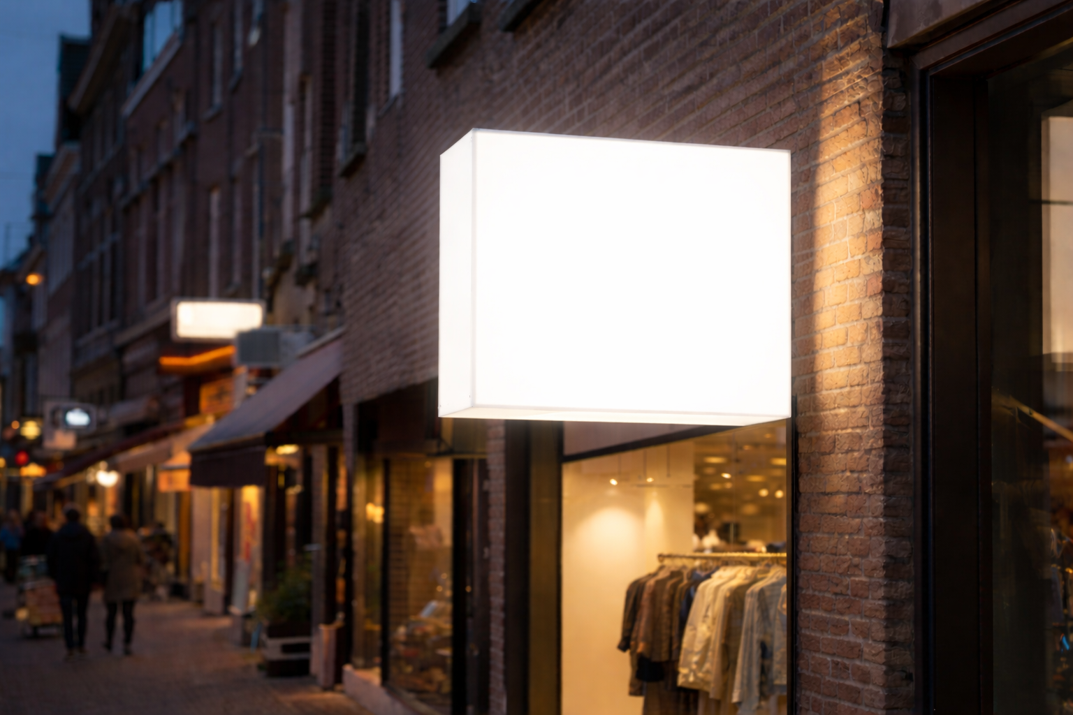 Vierkante opaal acrylaat lichtbak met beeldmerk, verlicht aan alle zijden, gemonteerd op een winkelgevel in een sfeervolle winkelstraat.